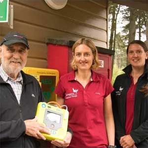 Kenneth Cooper holds a life-saving AED with Volunteer Rangers Keira Macfarland and Leo Hunt